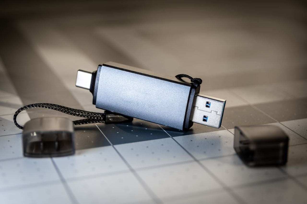 High-quality close-up of a dual USB-C and USB-A flash drive on a sleek grid-patterned background.